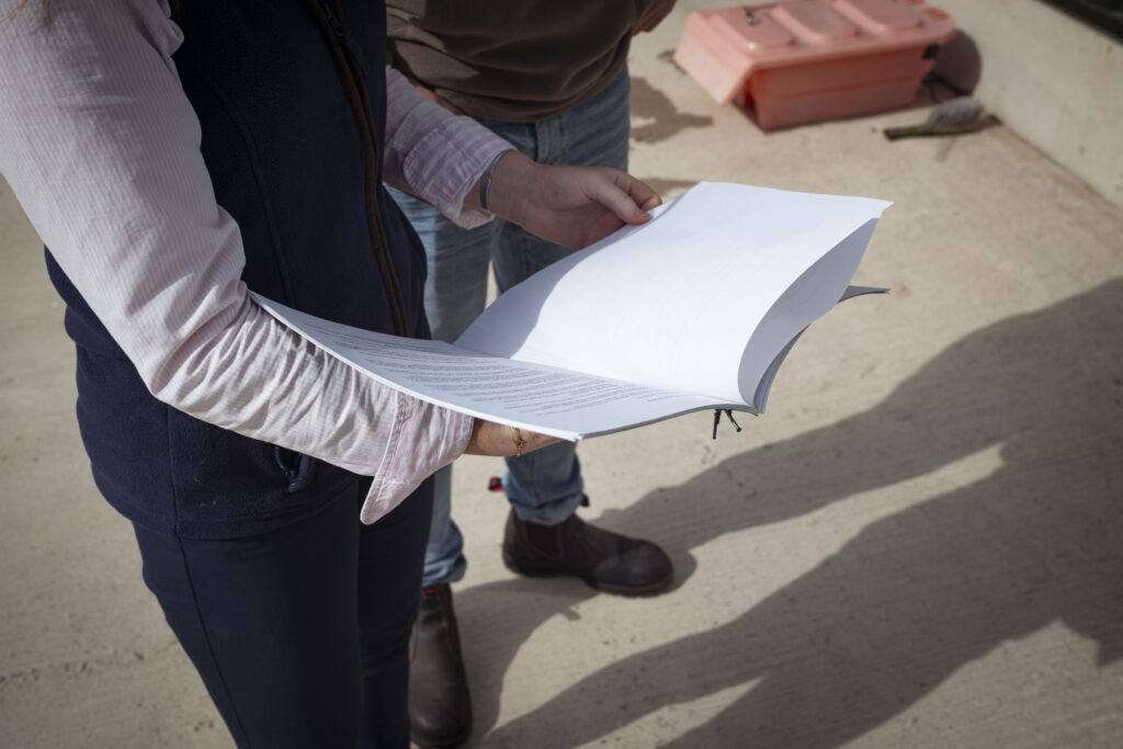 Two people reviewing farm business data documents on a farm