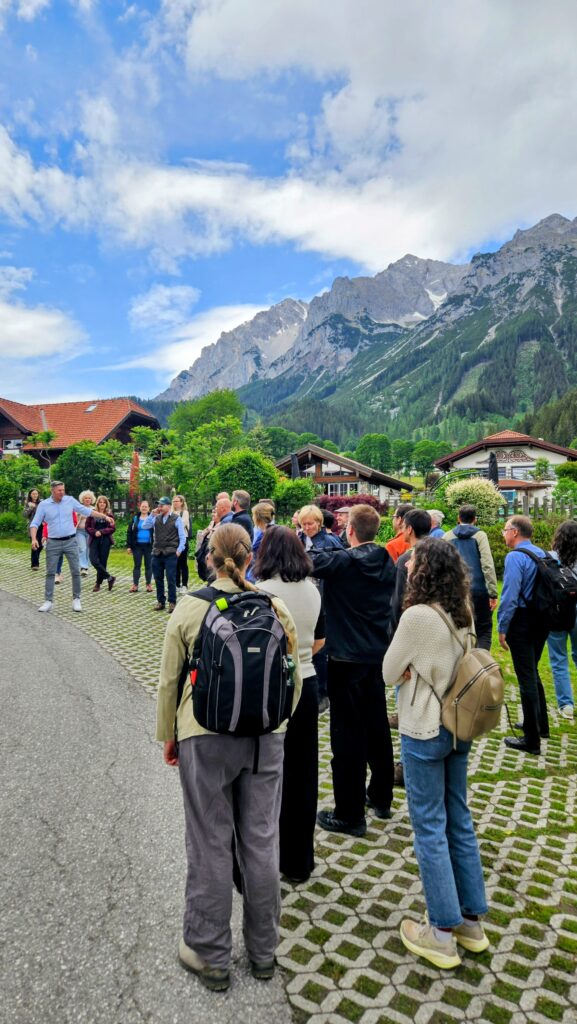 Conference delegates visiting an agritourism farm in Austria during the PACIOLI 30 conference, with alpine mountains in the background.